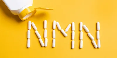 A yellow background with white pills spelling out NMN on it