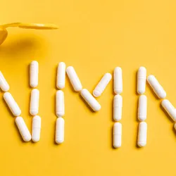 A yellow background with white pills spelling out NMN on it