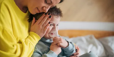 Mother taking care of her sick boy with an inhalation mask.