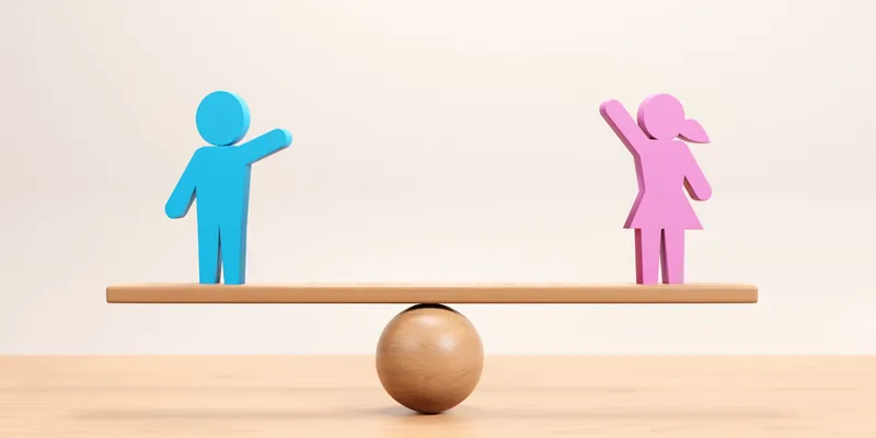 A female and male icon balanced on a wooden seesaw. 