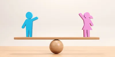 A female and male icon balanced on a wooden seesaw.