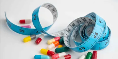 A blue measuring tape with pills on a white background
